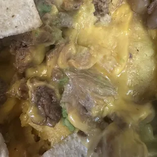 Gas station cheese, three slices of avocado and some grainy beef over chip crumbs (nachos)