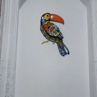 a colorful bird on a white wall