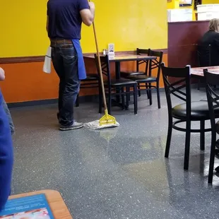 a man mopping the floor of a restaurant