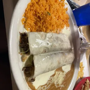 Steak burrito with cheese sauce, rice and beans
