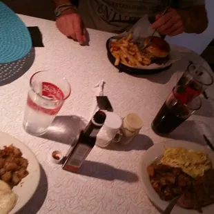 Burger and 2 med - rare steaks. One with over - easy eggs, the other scrambled.