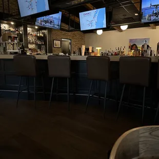 a row of bar stools in front of televisions