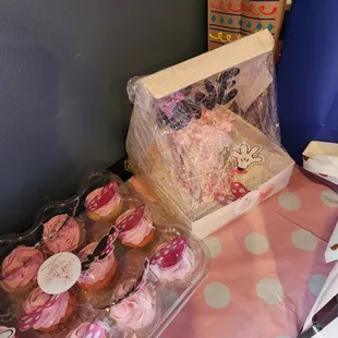 pink and white cupcakes in plastic containers