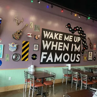 a dining area with tables, chairs, and a sign that says wake me up when i'm famous