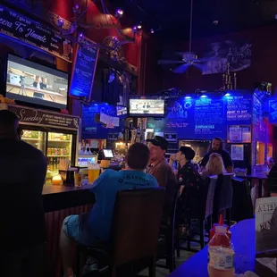 people sitting at a bar watching tvs