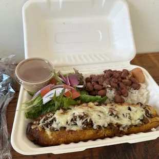 "Canoa" ripe plantain canoe stuffed with seasoned ground beef, cheese, salad, with a side of white rice and stewed beans.