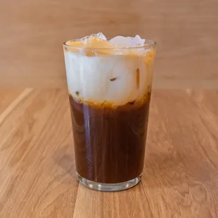a glass of iced coffee on a wooden table