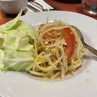 Som Thum (Papaya Salad) - Thai Style  This classic dish from Thailand consists of green papaya, chili, tomato, crushed peanuts mixed with lime juice, fish sauce and sugar.