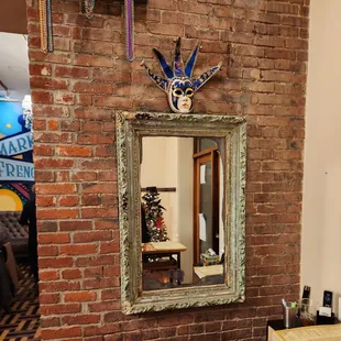 a mirror and a mask on a brick wall