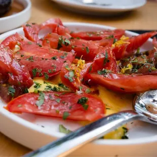 a plate of tomatoes and a spoon on a table