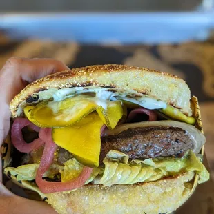 a hand holding a cheeseburger