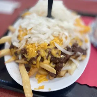 a plate of fries with cheese and onions