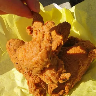 a hand grabbing a piece of fried chicken