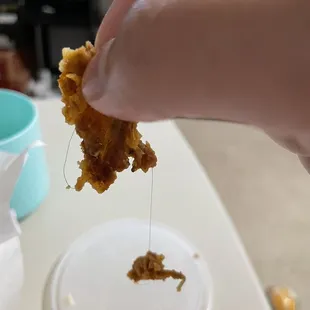 a hand holding a piece of fried chicken