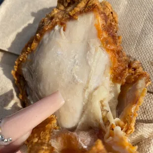 a hand holding a piece of fried chicken