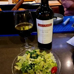 a plate of salad and a bottle of wine