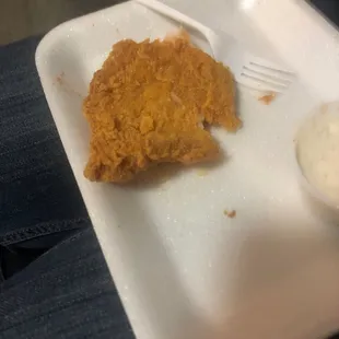 a piece of fried chicken with a side of sour cream