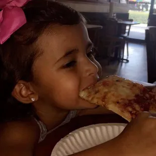 a little girl eating a slice of pizza