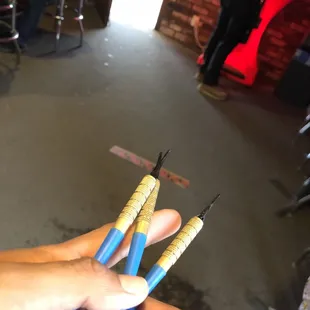 a hand holding three darts