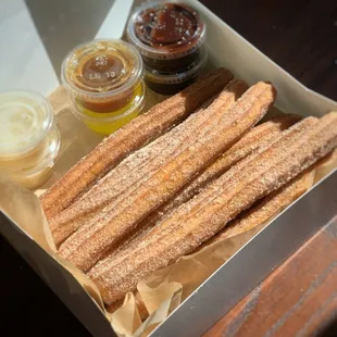 Churro Box 12 Fresh Churros with Chocolate (2) , Dulce De Leche (2), Caramel (1) and Lemon Curd Sauce (1)