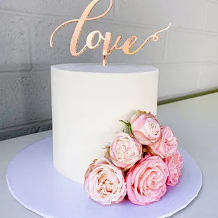 a white cake with pink roses