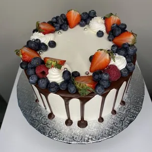 a chocolate drip cake with strawberries and blueberries