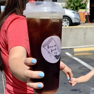 a woman holding a cup of iced coffee