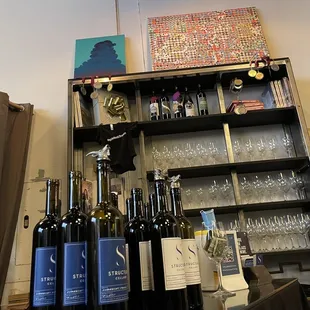 a shelf of wine bottles and glasses