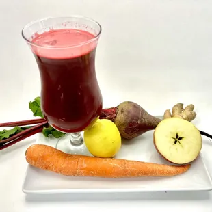 a glass of juice, carrots, apples, and a beet