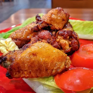 a plate of chicken wings, tomatoes and lettuce