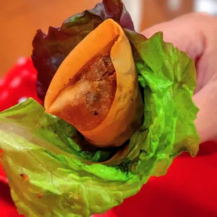 a hand holding a sandwich with lettuce