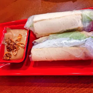 a red plate with a sandwich and dipping sauce