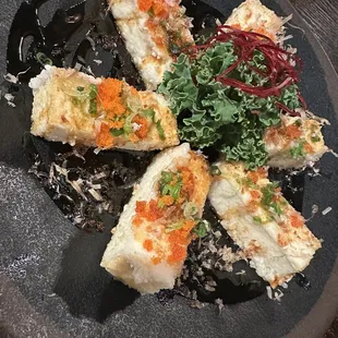 four pieces of sushi on a black plate