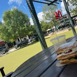 a sandwich and a cup of coffee on a picnic table