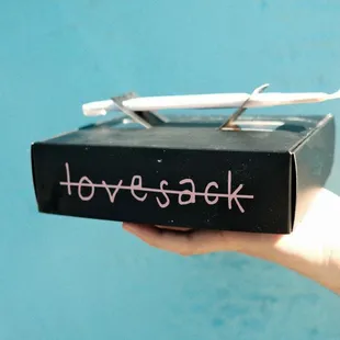 a hand holding a black box with the word lovesack written on it