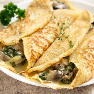 a plate of crepes with mushrooms and spinach