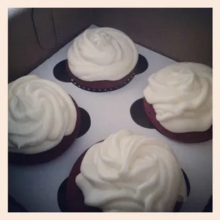 four chocolate cupcakes with white frosting