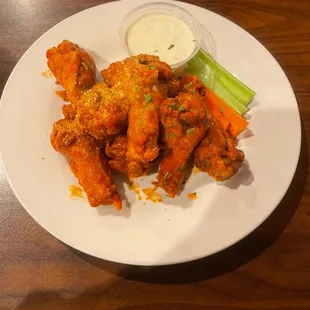 a plate of chicken wings with celery and ranch dressing