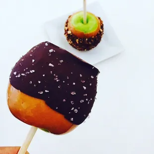 a hand holding a chocolate covered apple