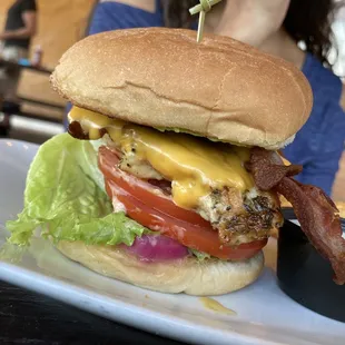 a burger with bacon, lettuce, tomato, and cheese