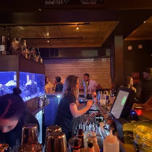 people sitting at a bar with a fish tank in the background