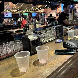 a bar with cups and a cell phone