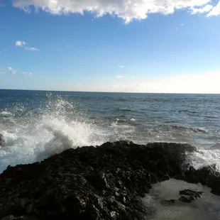 Another view of waves crashing.against the shore rocks.