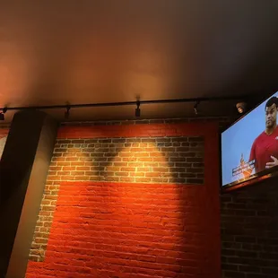 a television on a brick wall