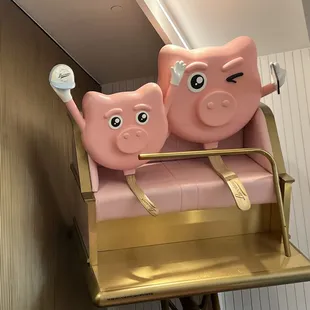 two pink piggys on a gold chair