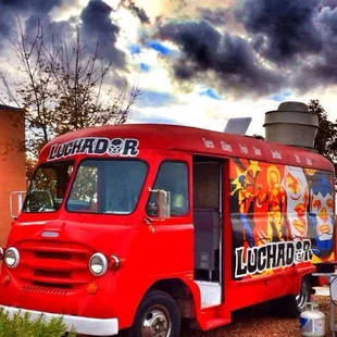 a red food truck parked in front of a building