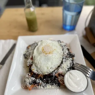 Chilaquiles with black beans, sour cream top with an egg