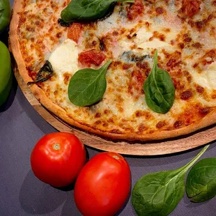 a pizza with spinach and tomatoes