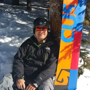 a man sitting in the snow with his snowboard