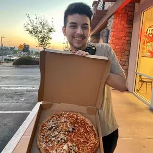 a man holding a box of pizza